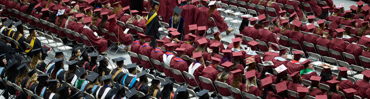 graduating students in cap and gown sitting during commencement ceremony