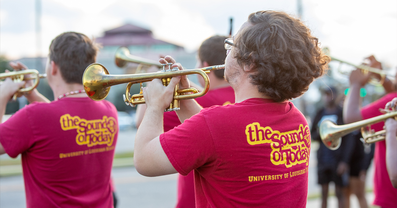Young people play the trumpet with their backs to the camera. Their t-shirts read "Sound of Today."
