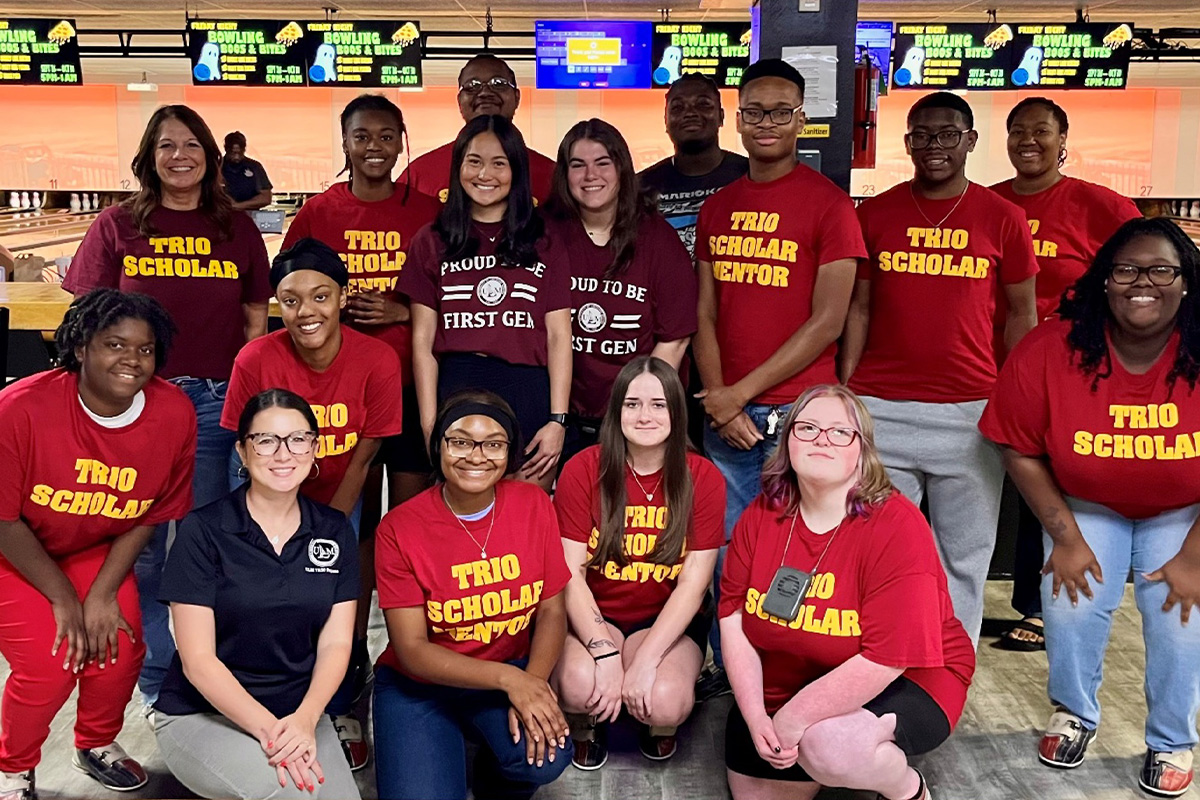 A group of people pose and smile at a bowling alley. 