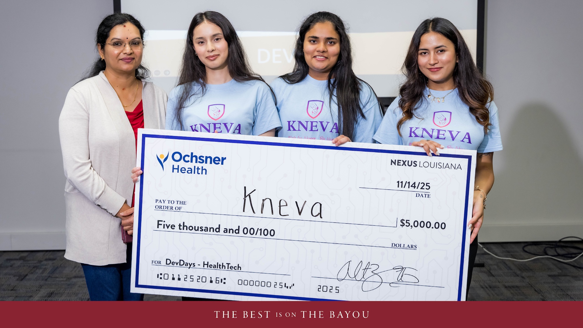 A group of four women smile while holding a large check. 