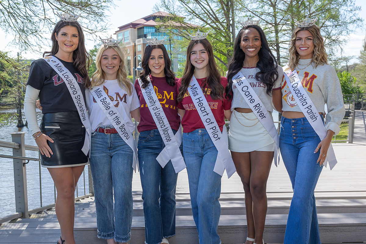 Six ULM students who are contestants in Miss Louisiana pose with the bayou and the ULM Library in the background. 