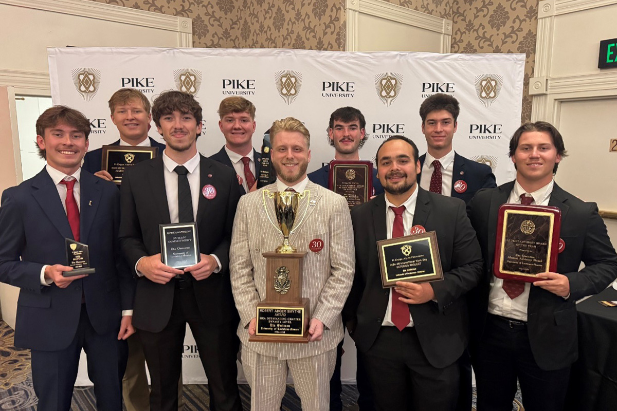 A group of students from the Pi Kappa Alpha Fraternity holding awards and smiling. 