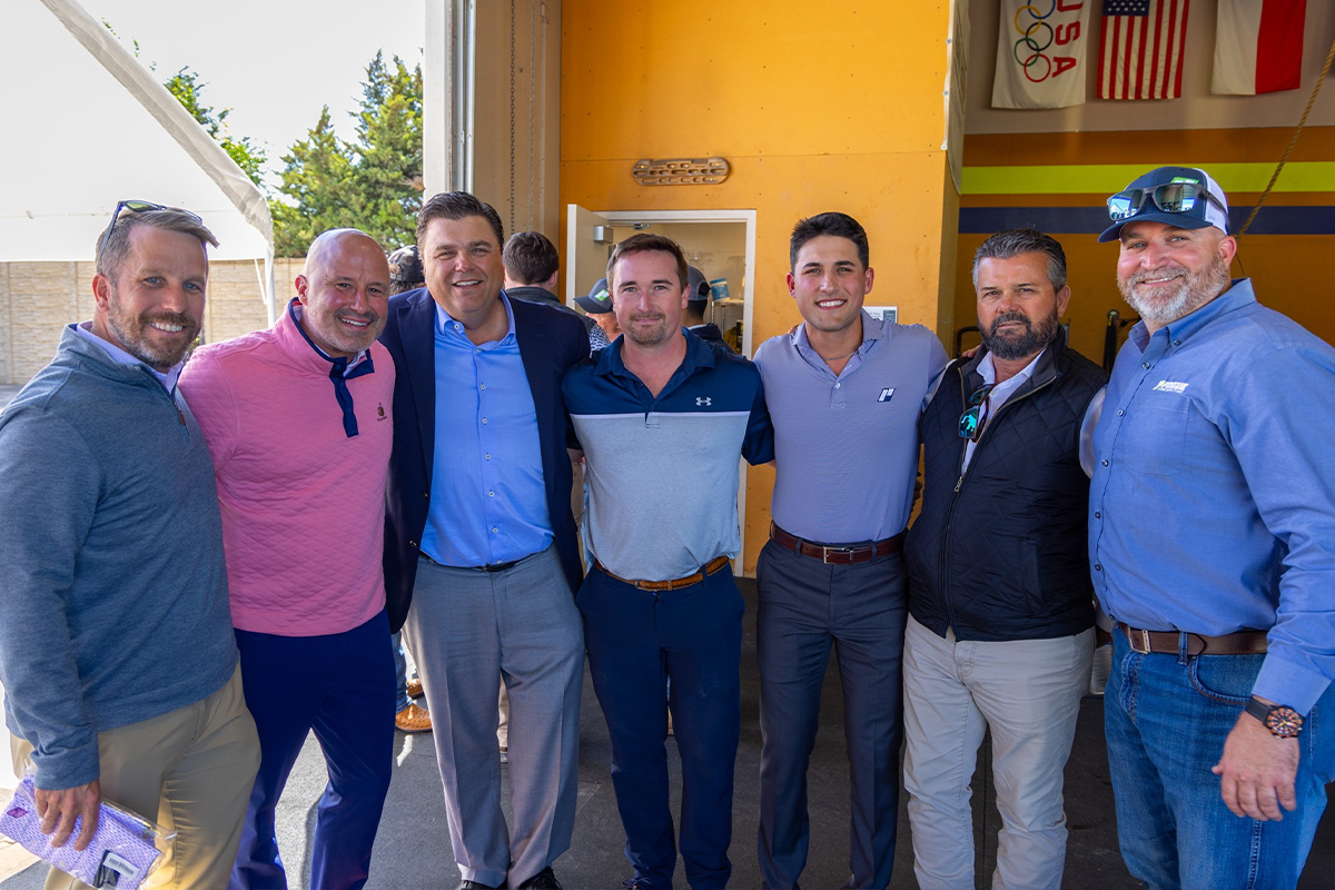 A group of seven men standing in a row and smiling. 
