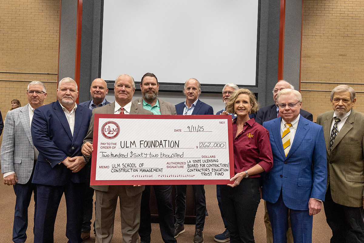 A group of people pose with a large check. 