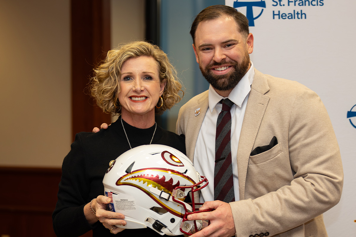 ULM President Dr. Carrie Castille presents new Director of Athletics SJ Tuohy with a helmet at his introductory press conference.  