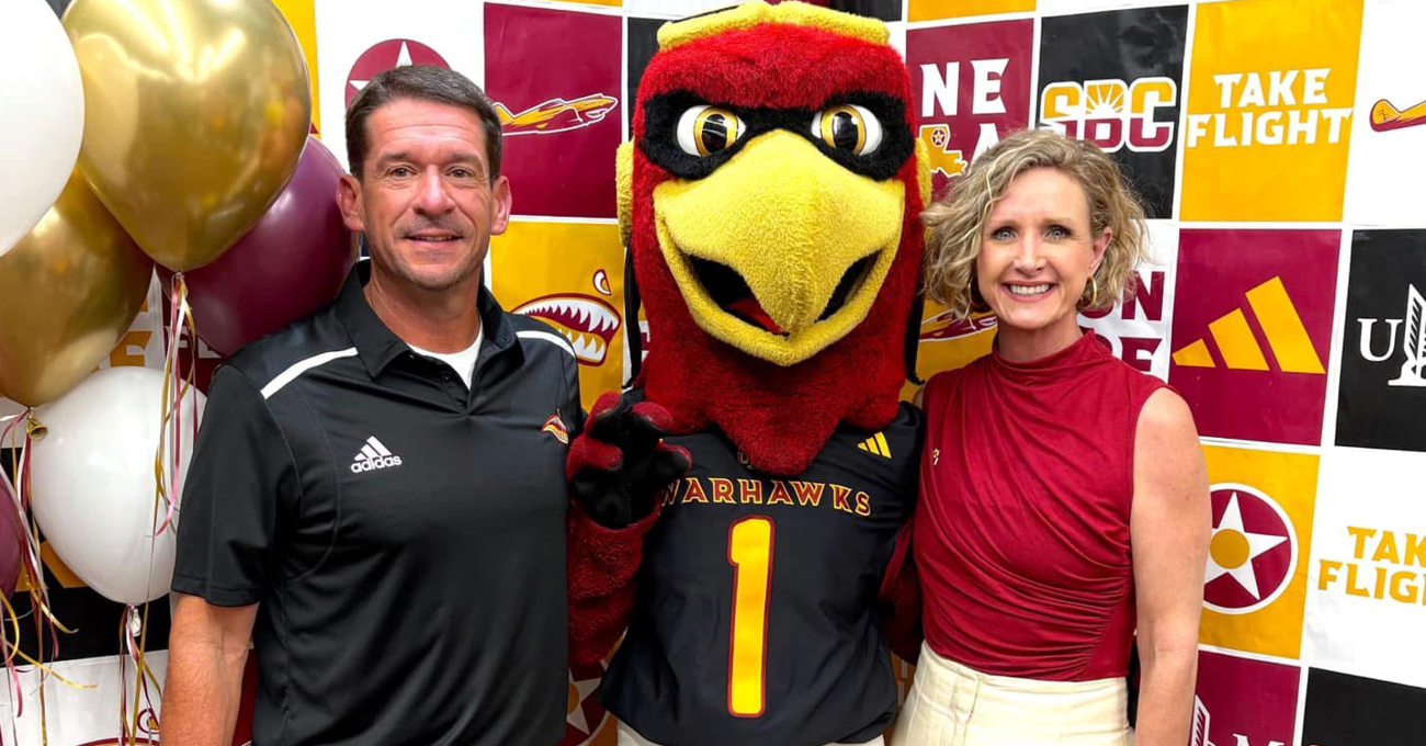A man and a woman pose with a person in a bird mascot outfit.